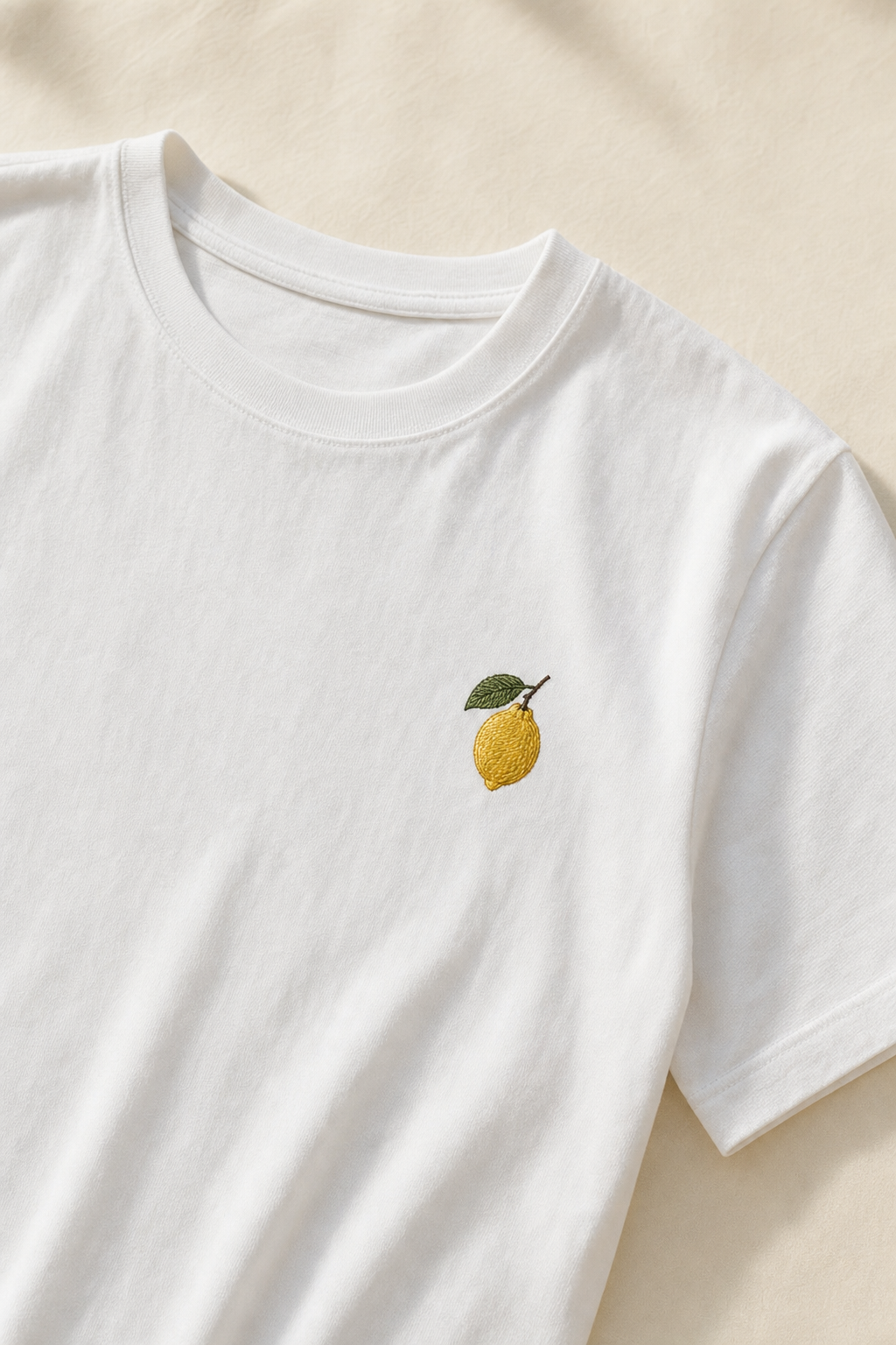The Founding Tee — front view, white cotton with a small embroidered lemon on the chest
